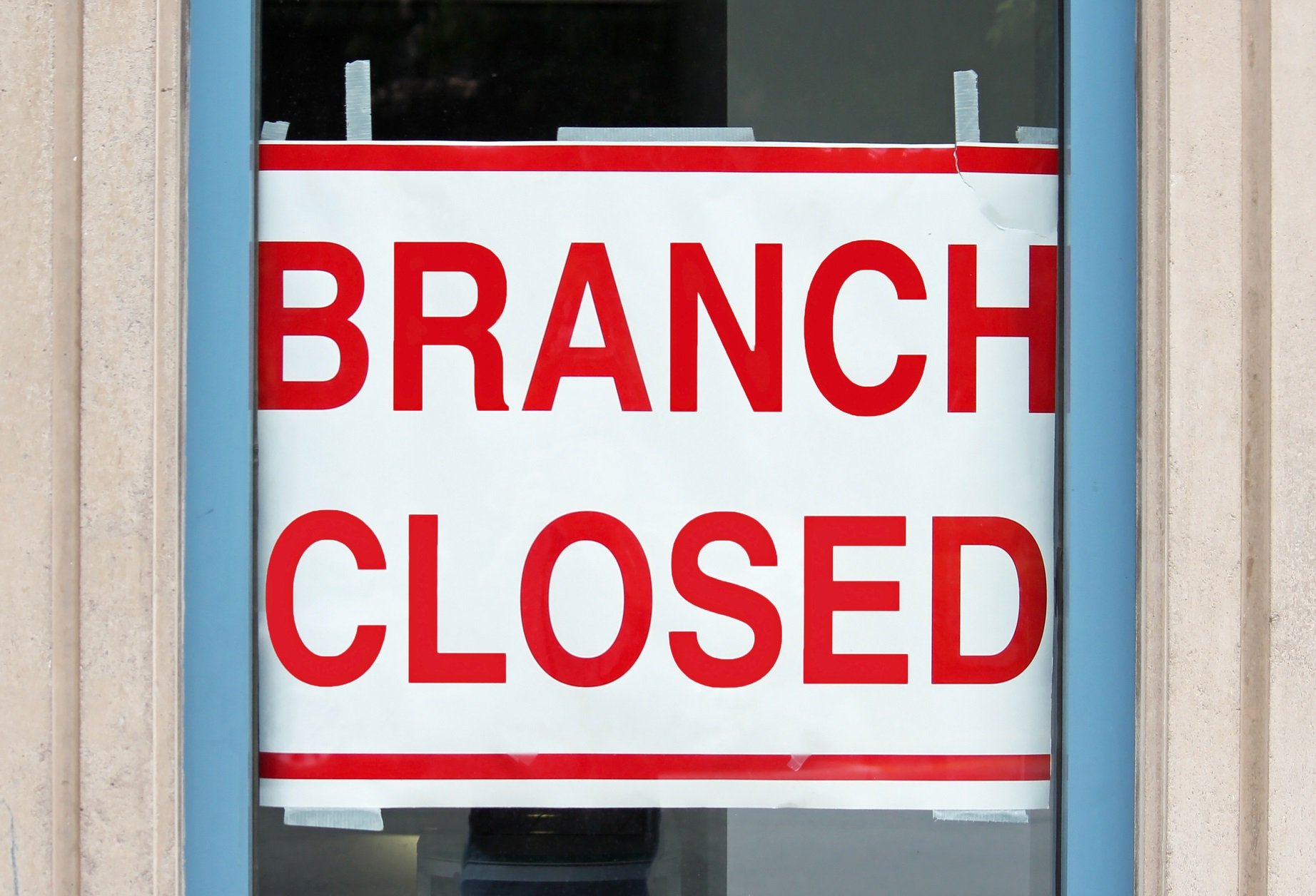 Sign that reads "branch closed" in a bank window.