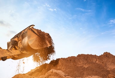 A shovel filled with sand from a big pile.