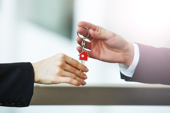 A person handing another person keys to a home.