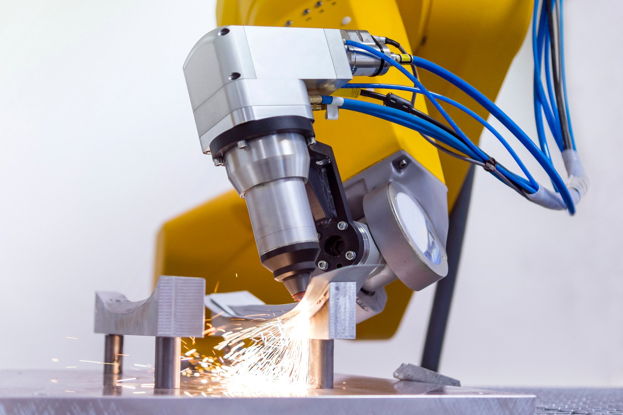 Laser on robotic arm cutting metal.