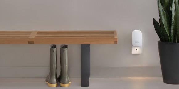 Eero node plugged into an outlet, next to a potted plant, a bench, and a pair of rain boots