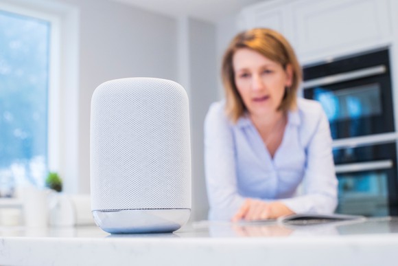 Woman in background as she gives verbal commands to a smart speaker