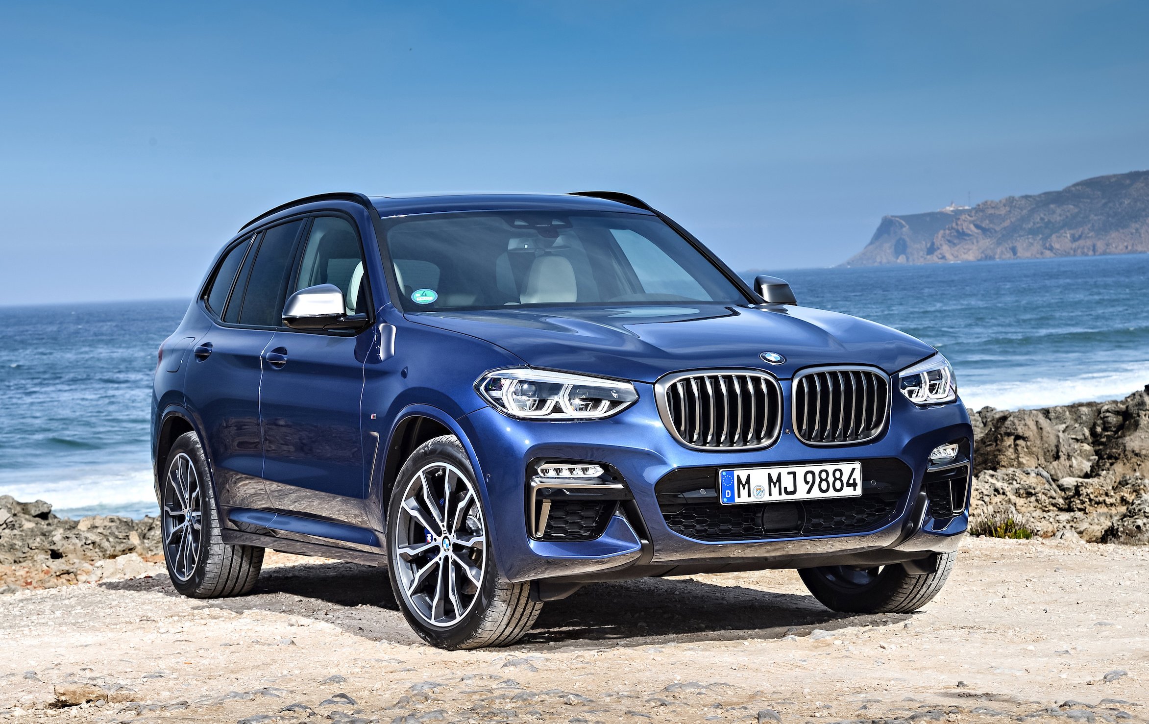 A blue 2018 BMW X3, a compact luxury crossover SUV, parked on a beach