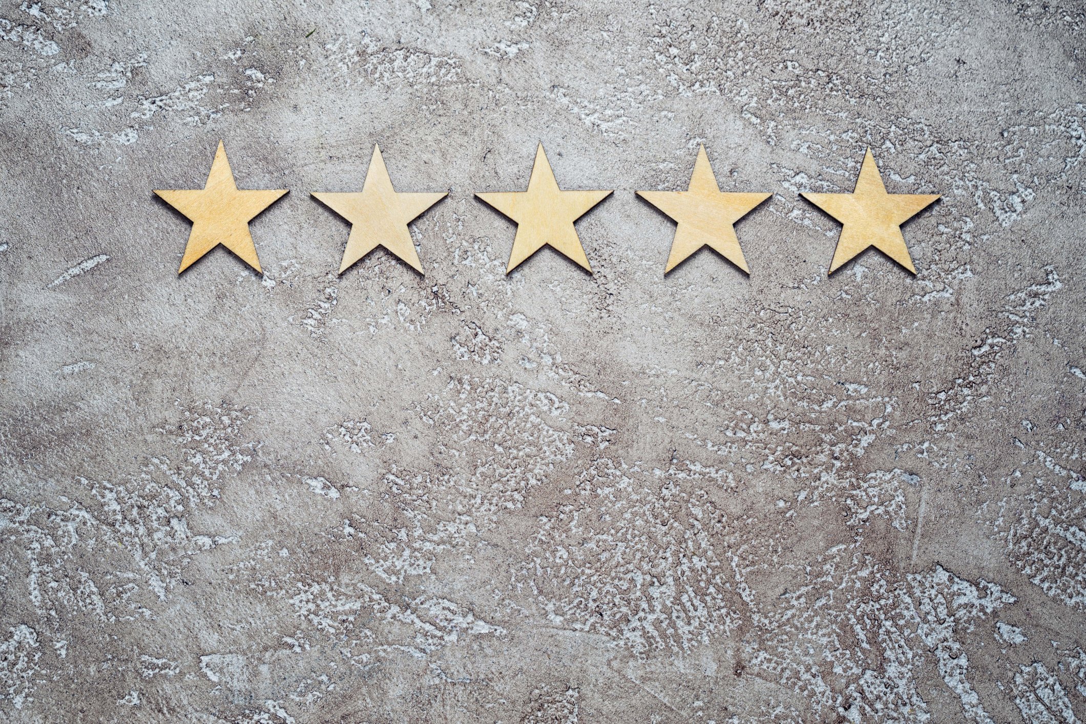Five gold stars in a row on a concrete floor.