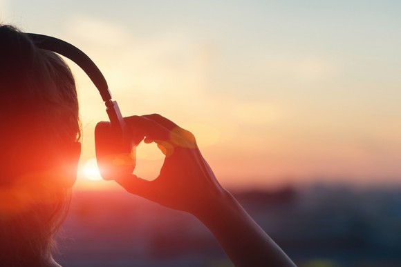 Woman with headphones watching sunset.