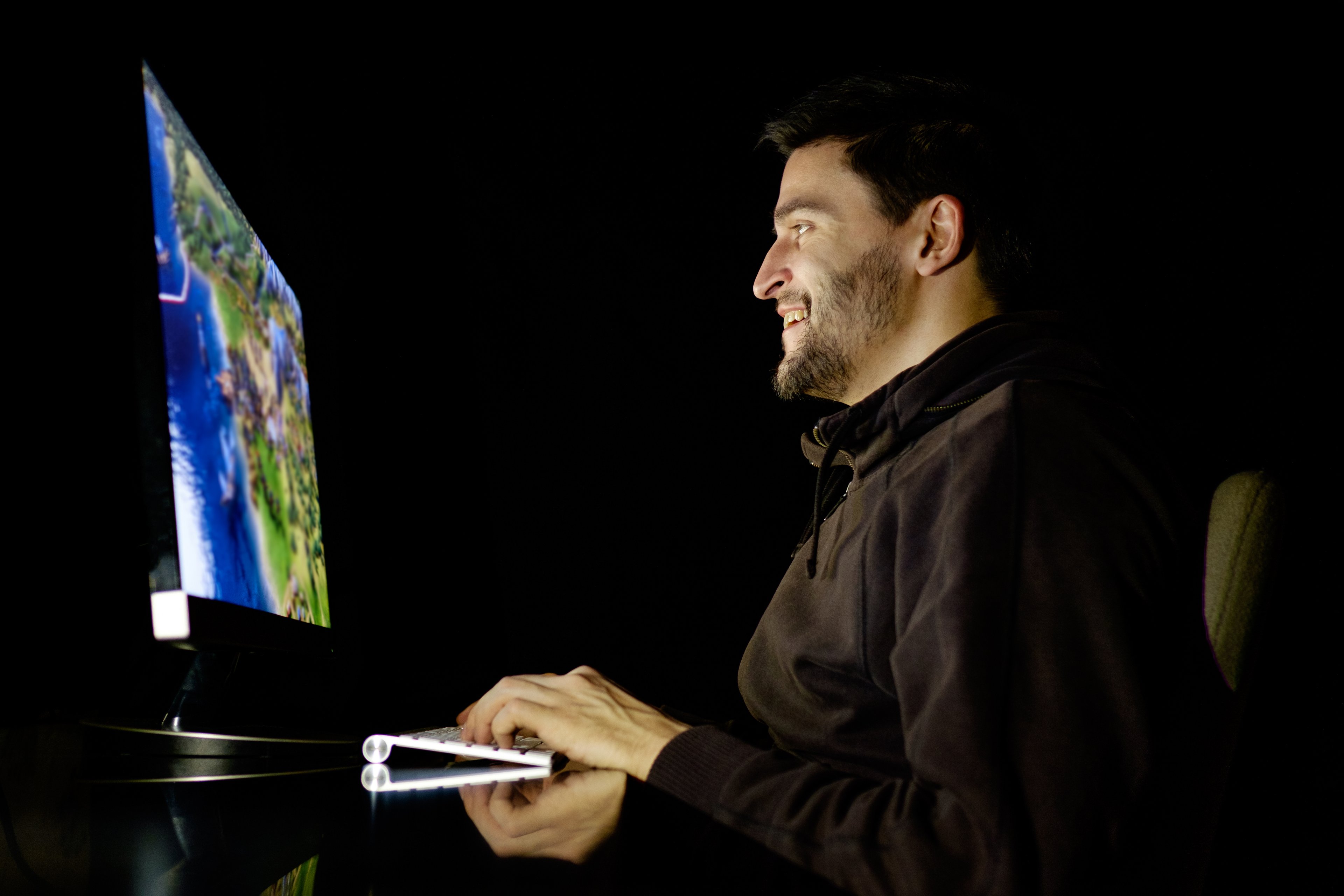 Man sitting at desk playing a video game on computer.