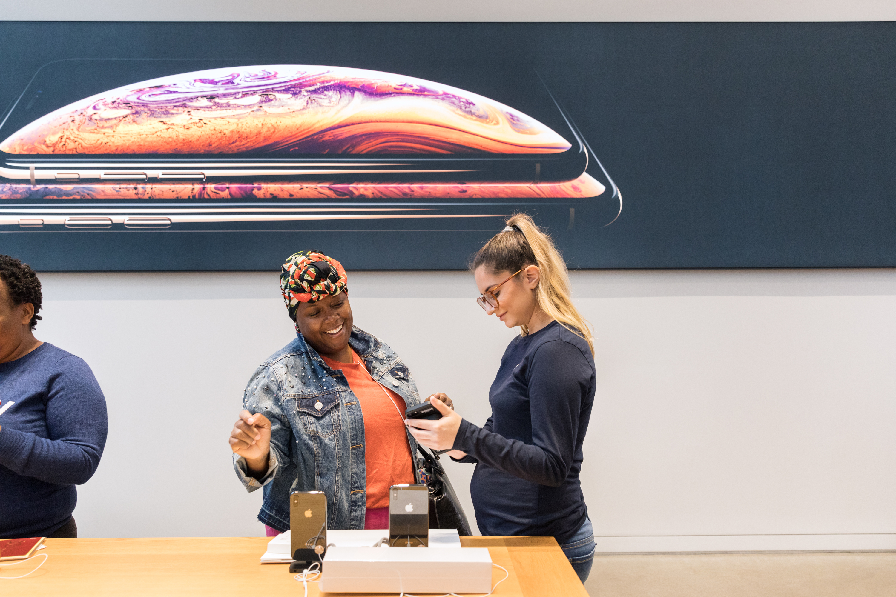 A customer and an Apple store employee in front of an iPhone display.