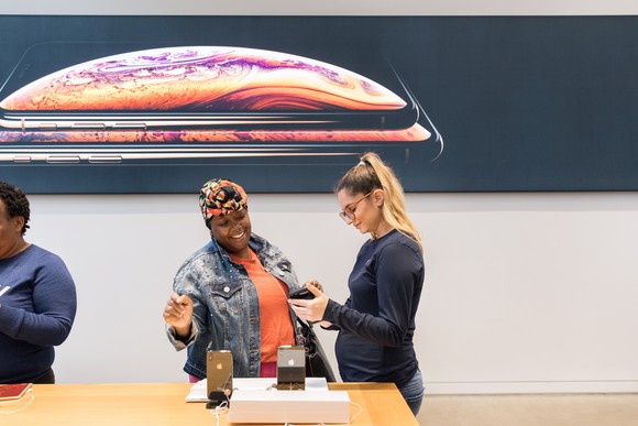 A customer and an Apple store employee in front of an iPhone display.