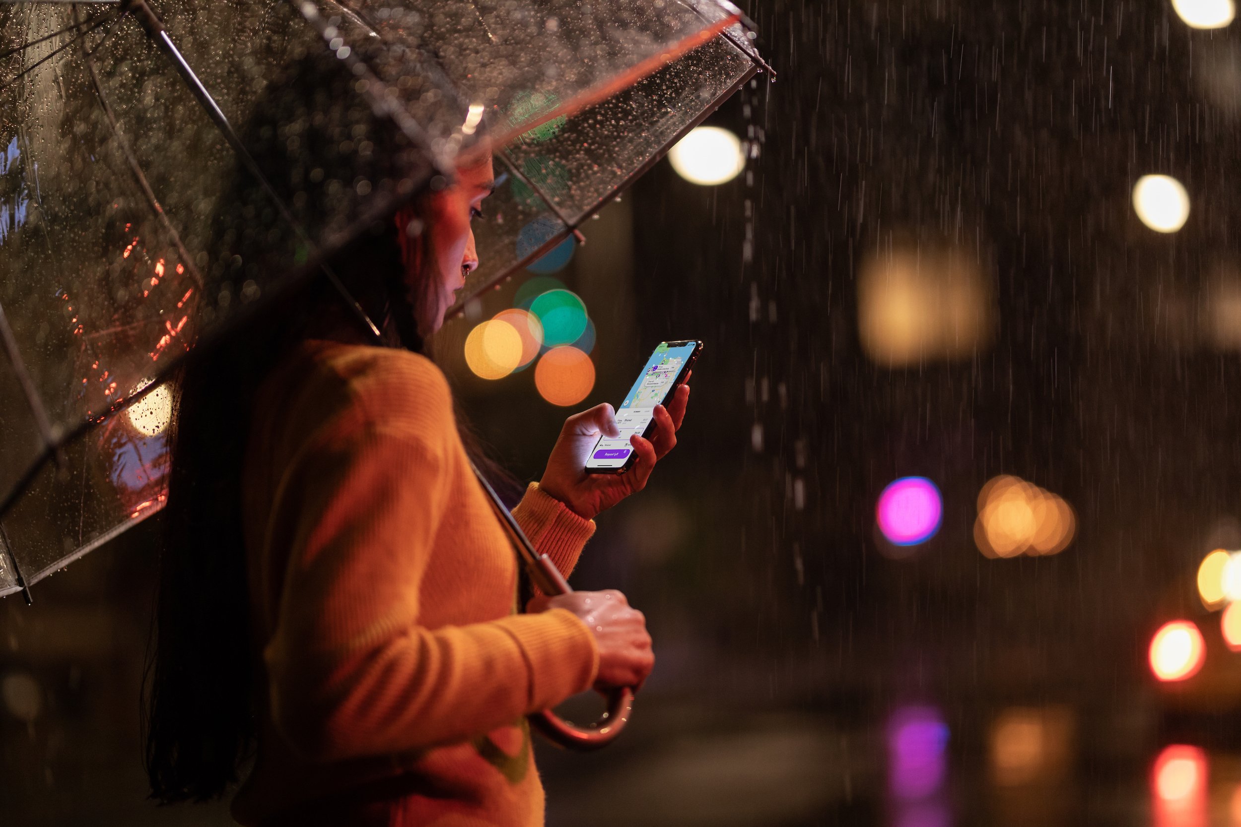 Woman standing in the rain holding an iPhone.