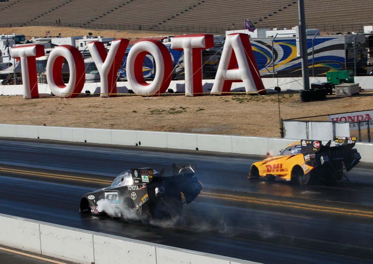 Two drag cars racing in front of the Toyota logo.