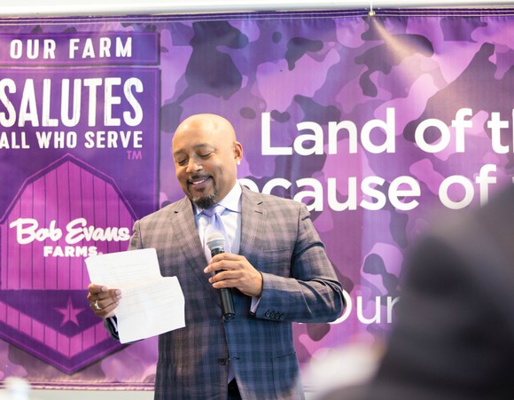 Daymond John speaking on stage at the Bob Evans Farms "Heroes to CEOs" event