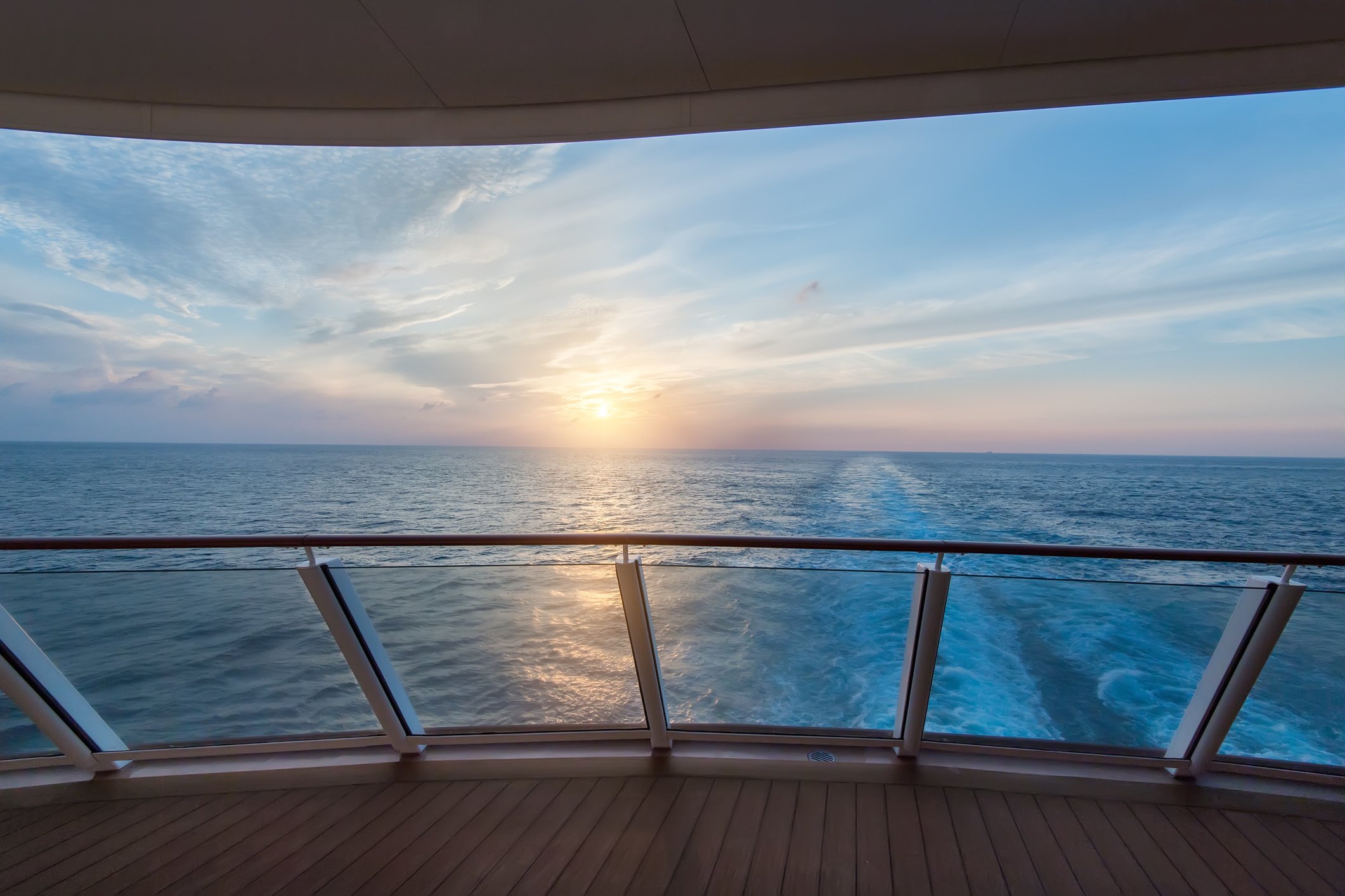 Scenic view of a cruise ship's wake seen from the deck at sunrise.