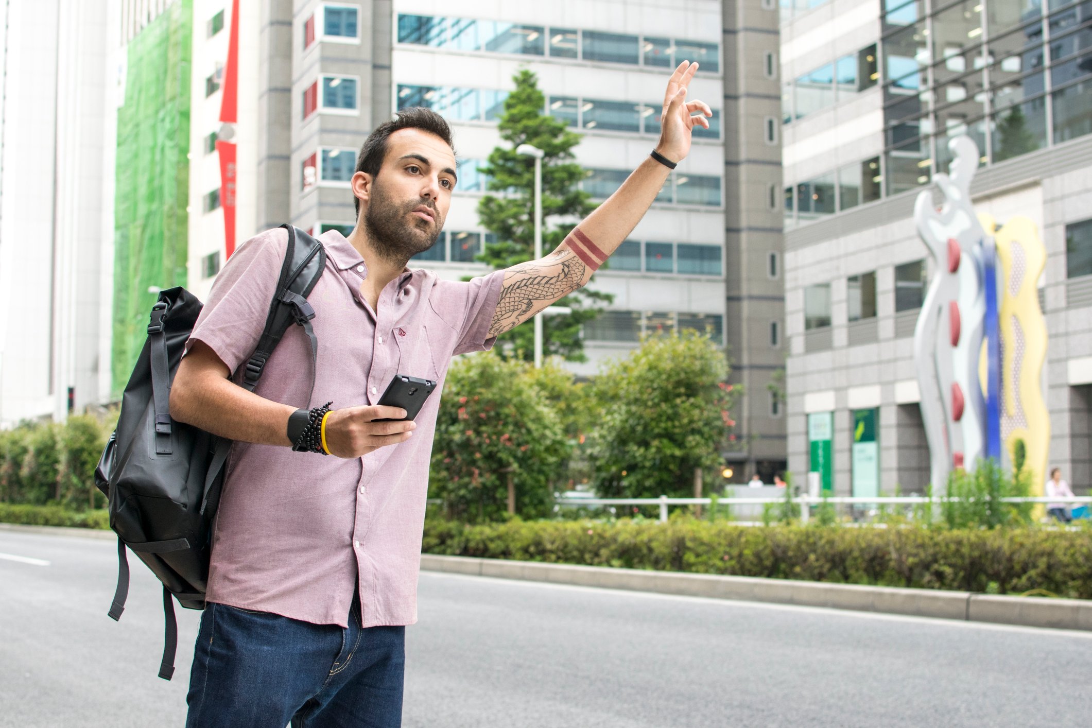 Young man holding a cellphone and hailing a ride