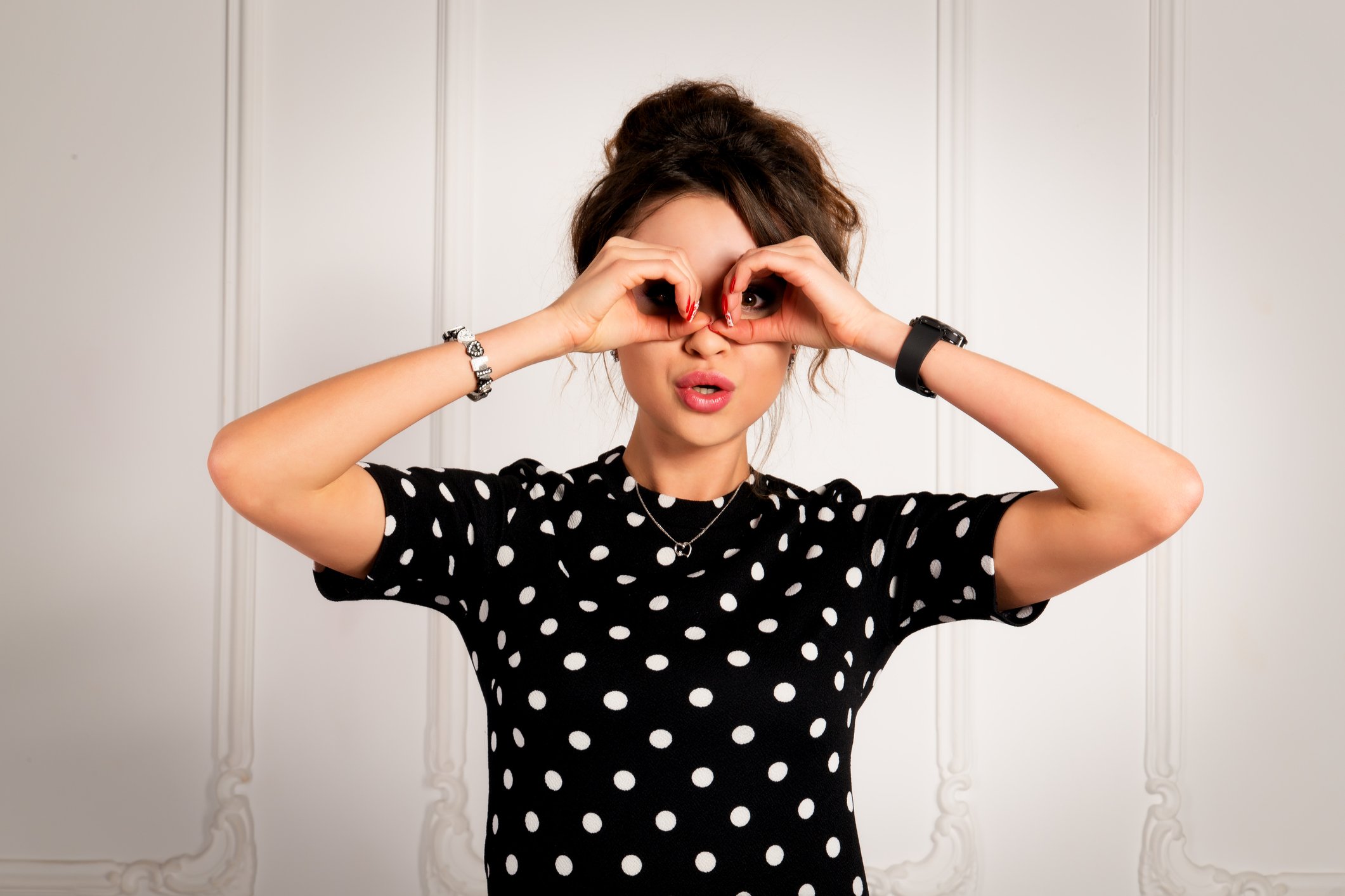 A woman holds her hands as if looking through a pair of binoculars.
