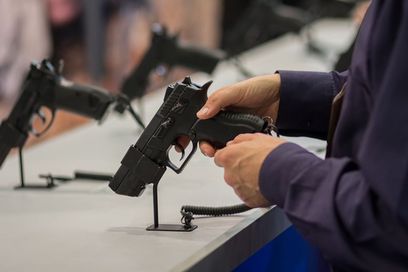 A person checking out a pistol at a gun show.