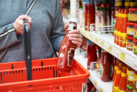 Shopper putting ketchup in a basket