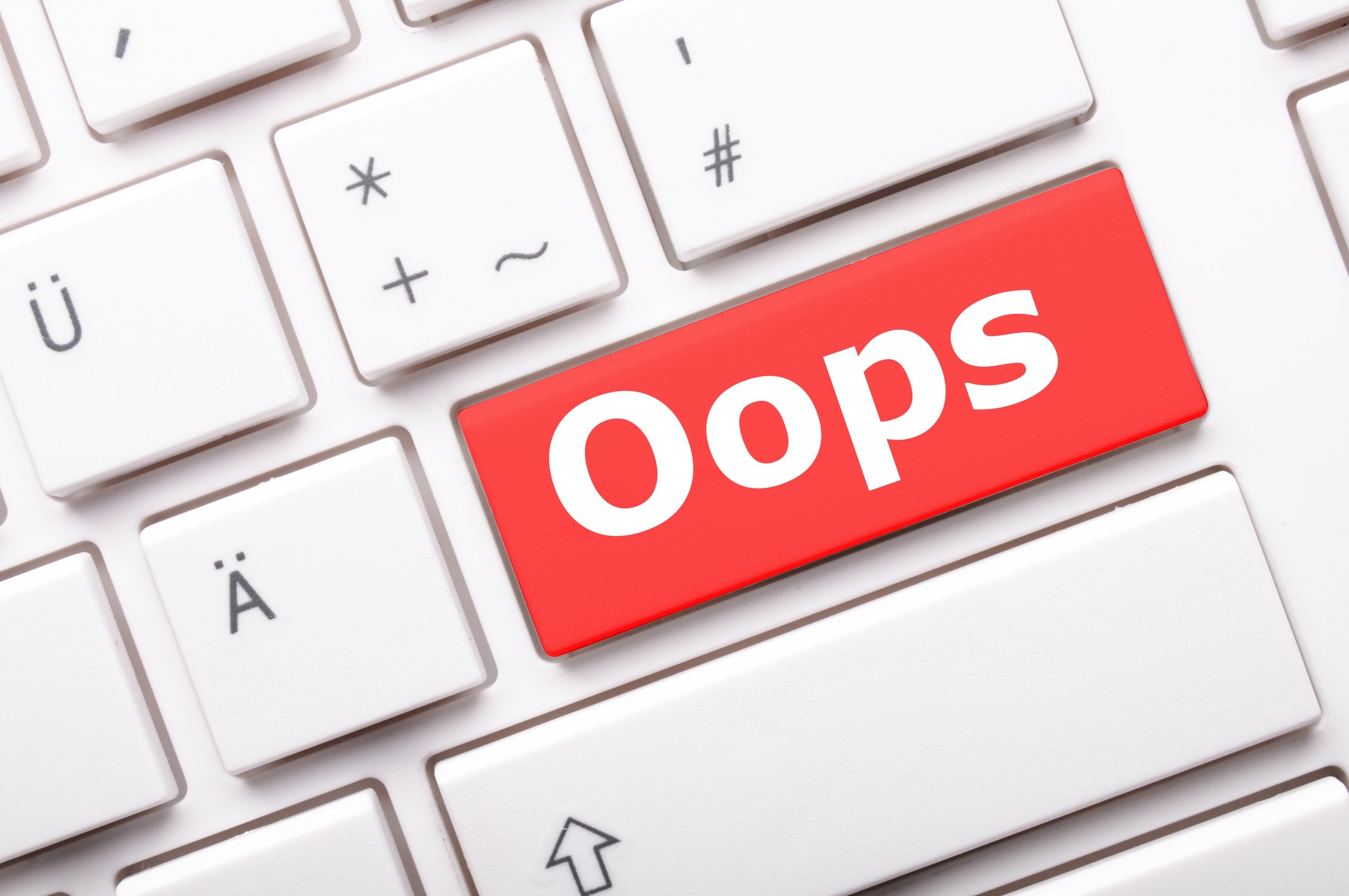 A white keyboard is shown, with a big red key labeled with the word oops.