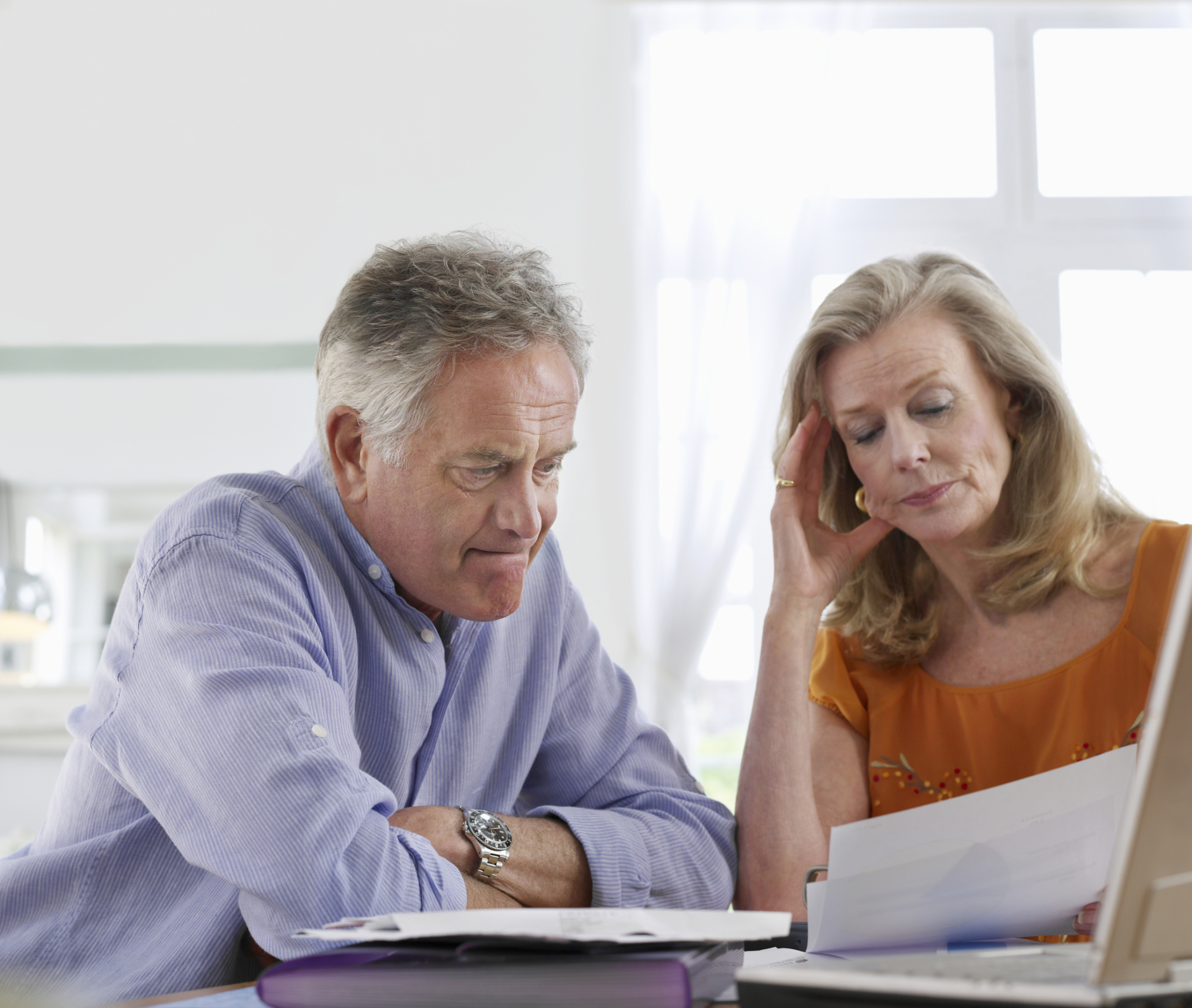 A visibly concerned retired couple examining their finances. 