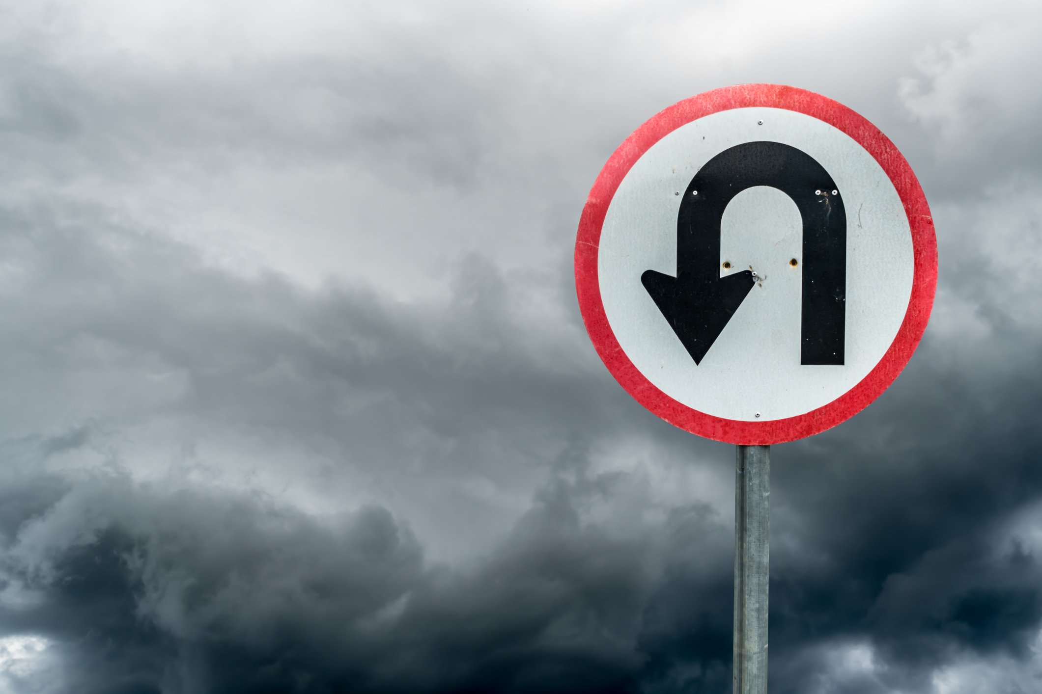 U-turn sign against a cloudy backdrop