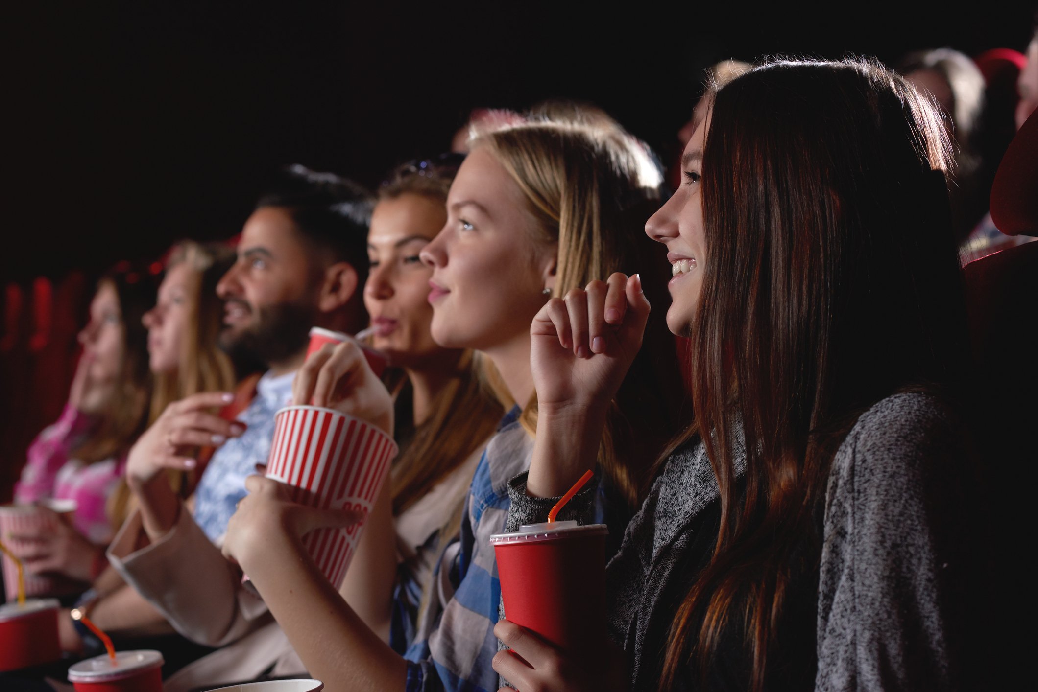 A group of young women watching a movie in a theater.