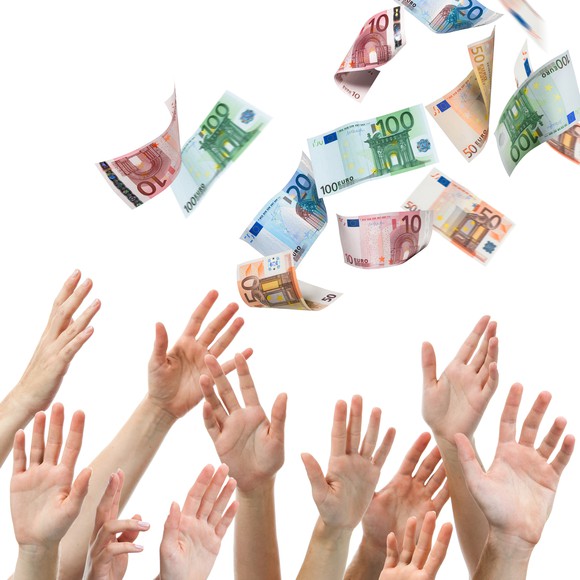 Hands catching foreign money as it falls from above.