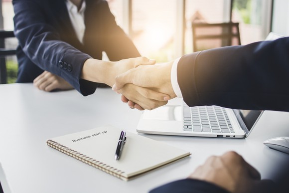 Two businessmen shaking hands across a table