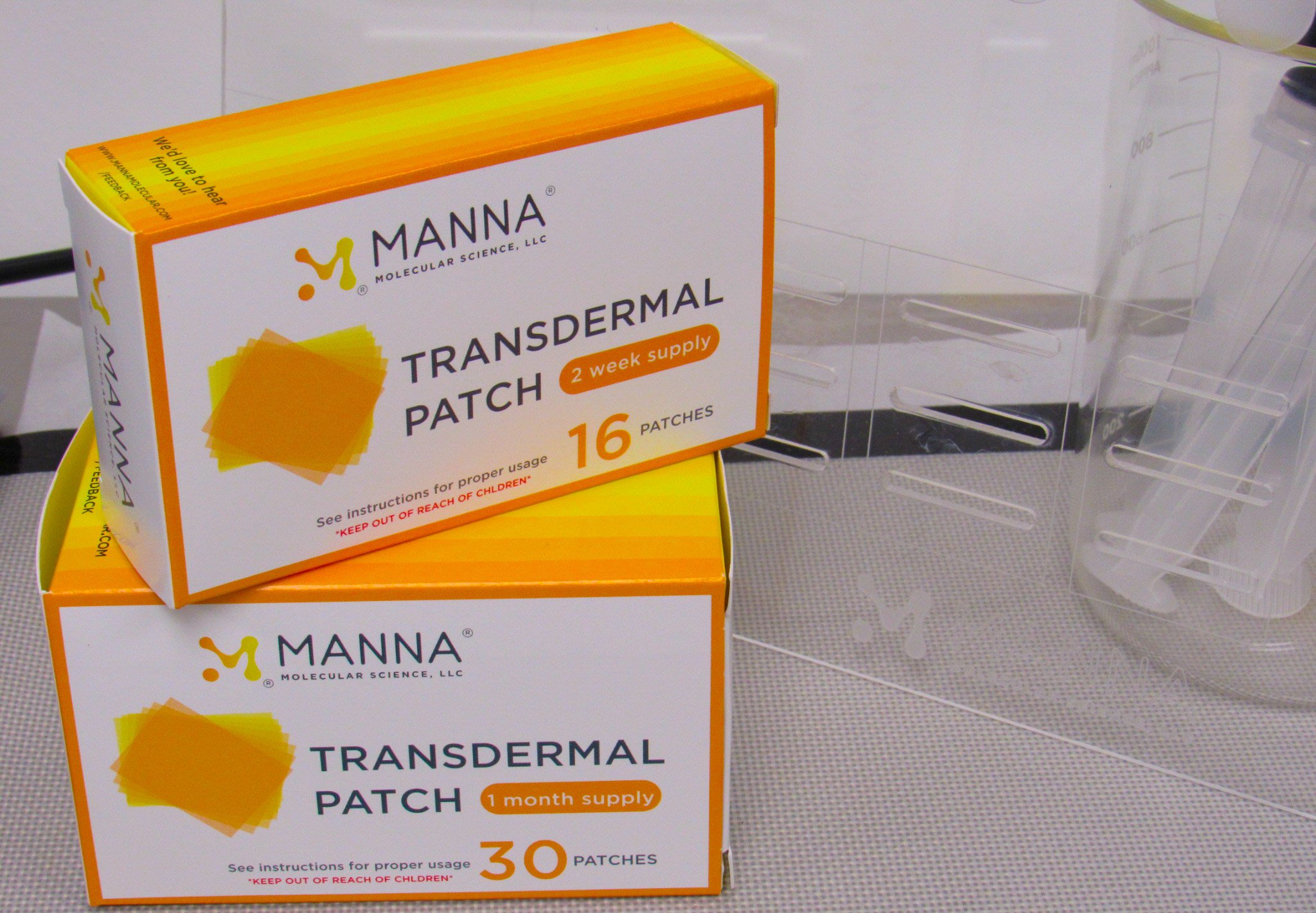 Two orange boxes labeled Manna transdermal patch, on a gray table.