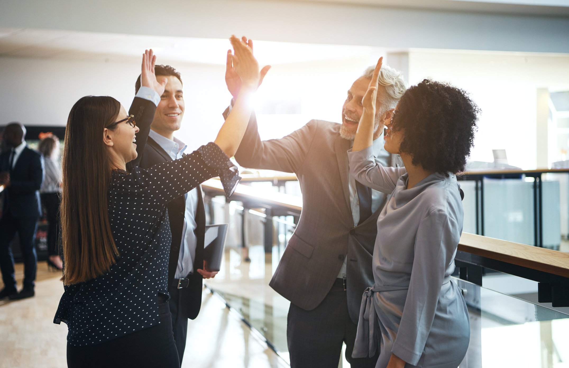Four business people giving high fives
