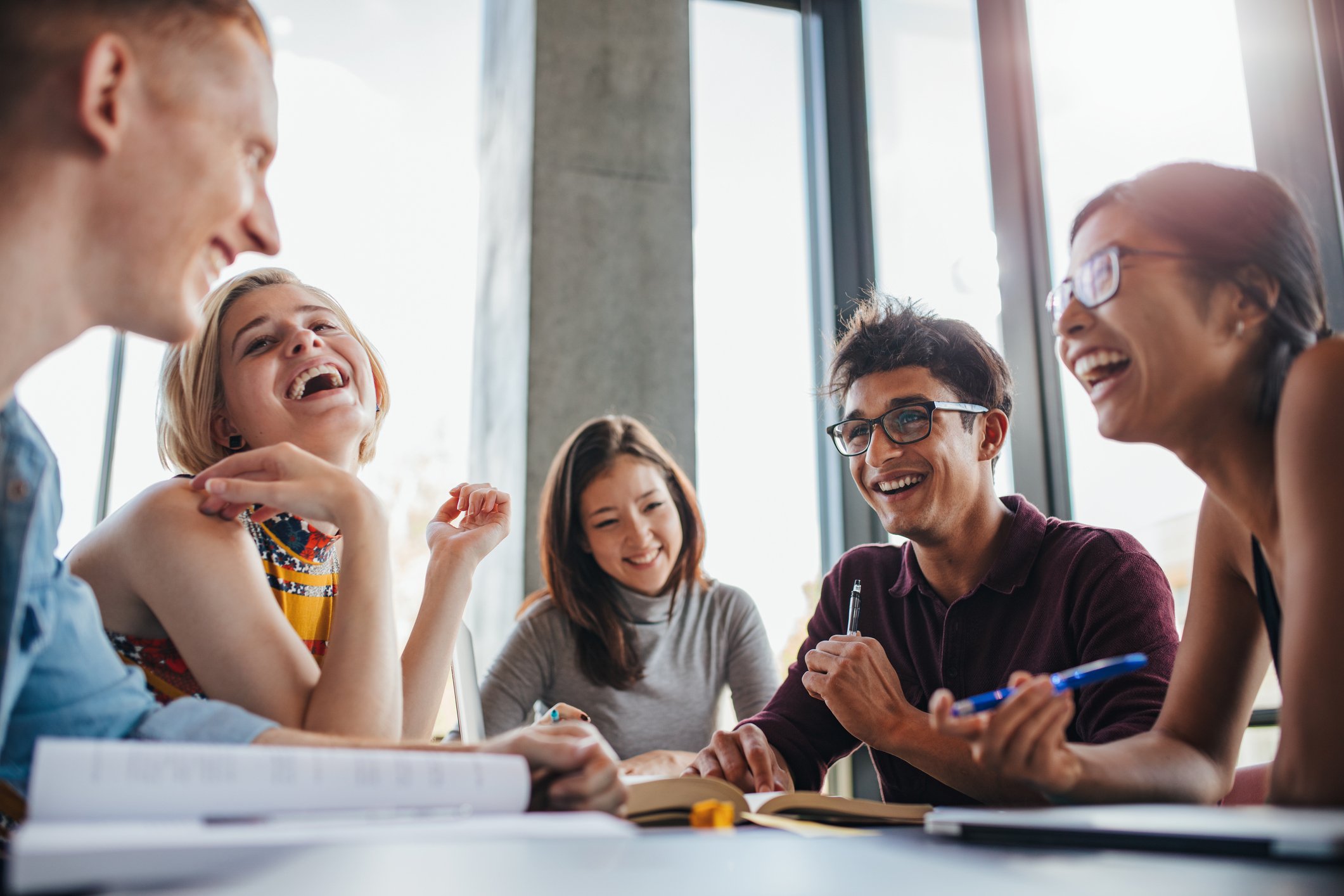 Young people laughing around a table.
