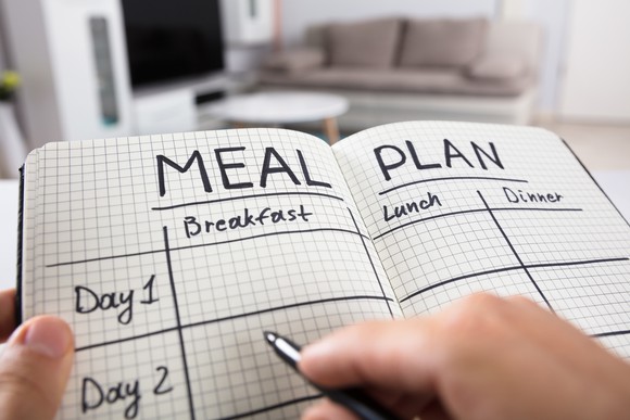 A woman marking notes in a "Meal Plan" book.