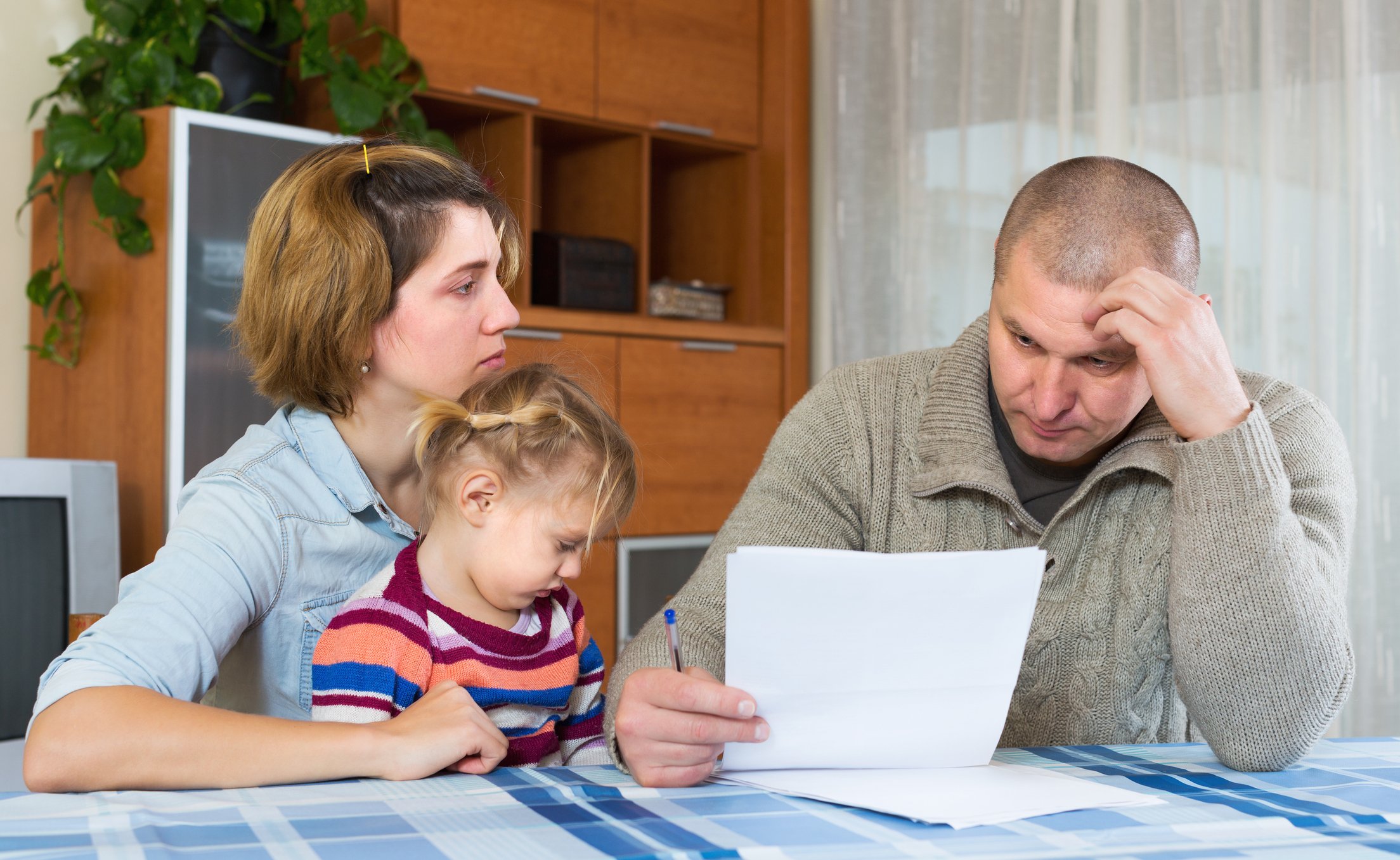 Man reading a document while woman sits next to him with young girl on her lap