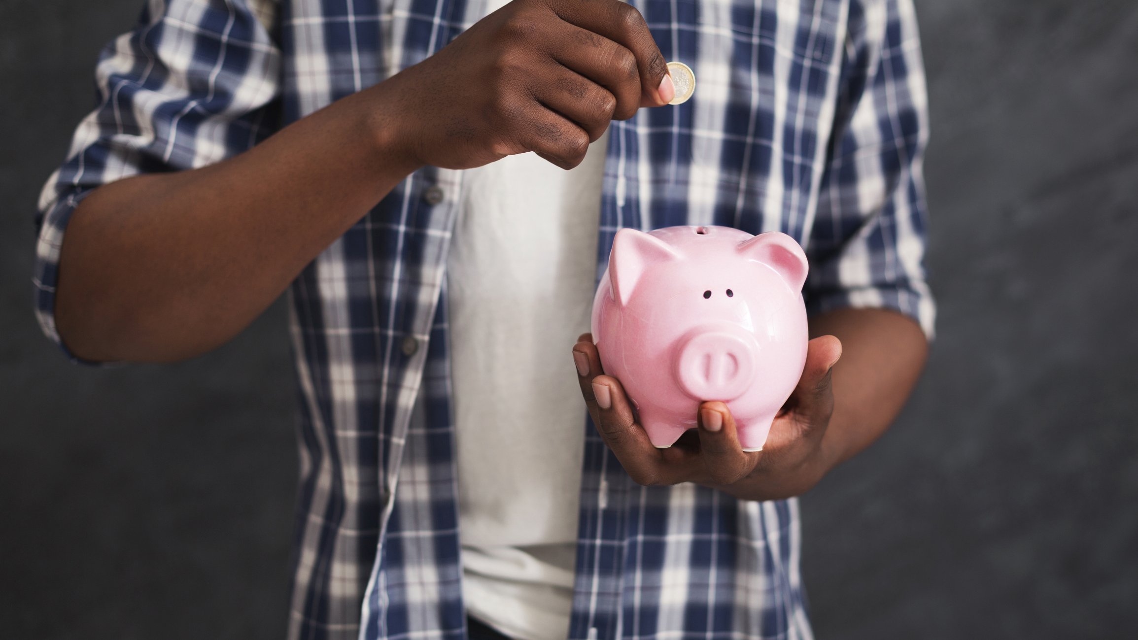 Man dropping coin into piggy bank