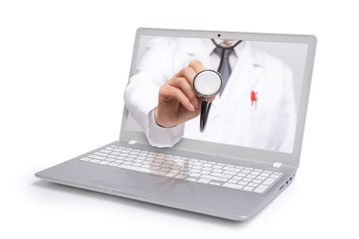 A laptop screen showing a doctor's arm reaching out holding a stethoscope