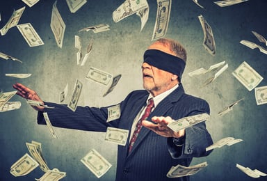 Blindfolded businessman chasing dollar bills
