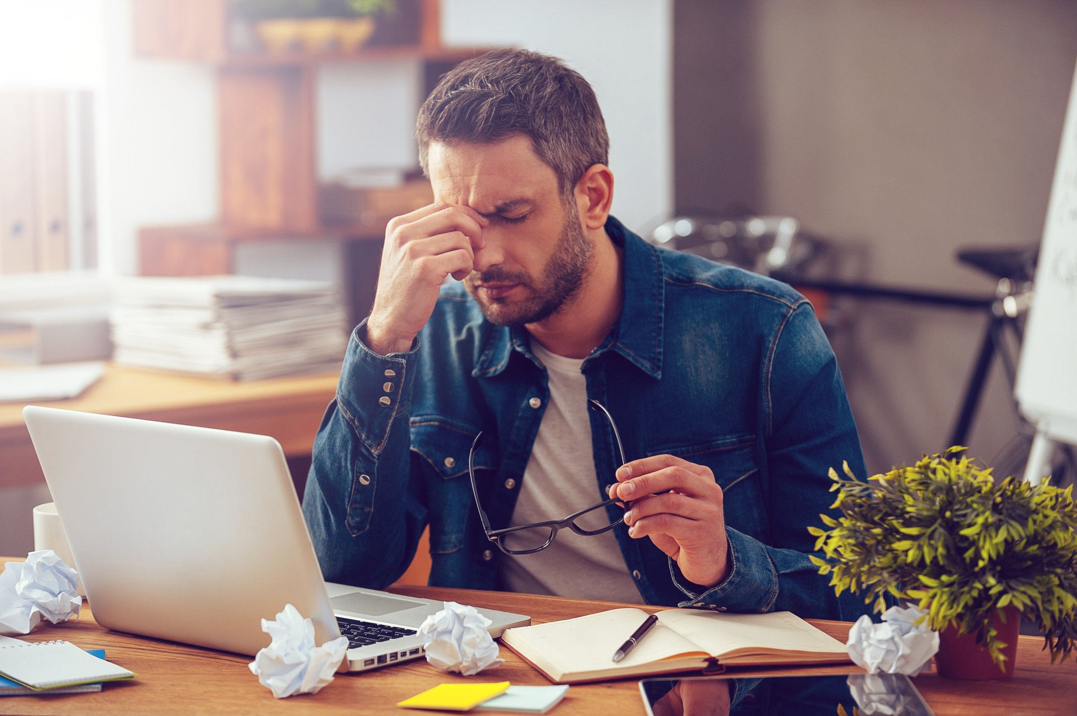 Man at laptop holding his face as if stressed.