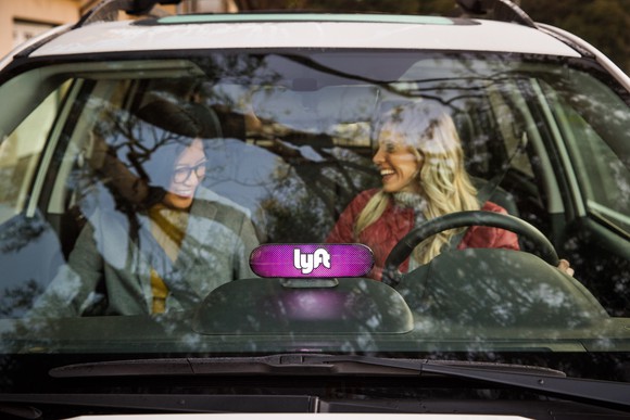 Two women sitting in the front seat of a Lyft car