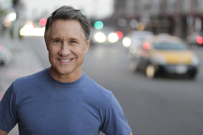 Smiling man with cars faded in the background