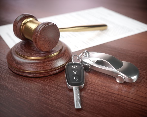 A gavel next to a miniature car attached to car keys.