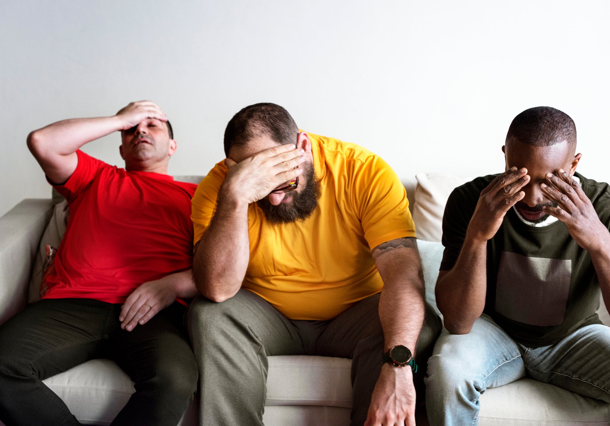 Three distressed guys on a sofa.