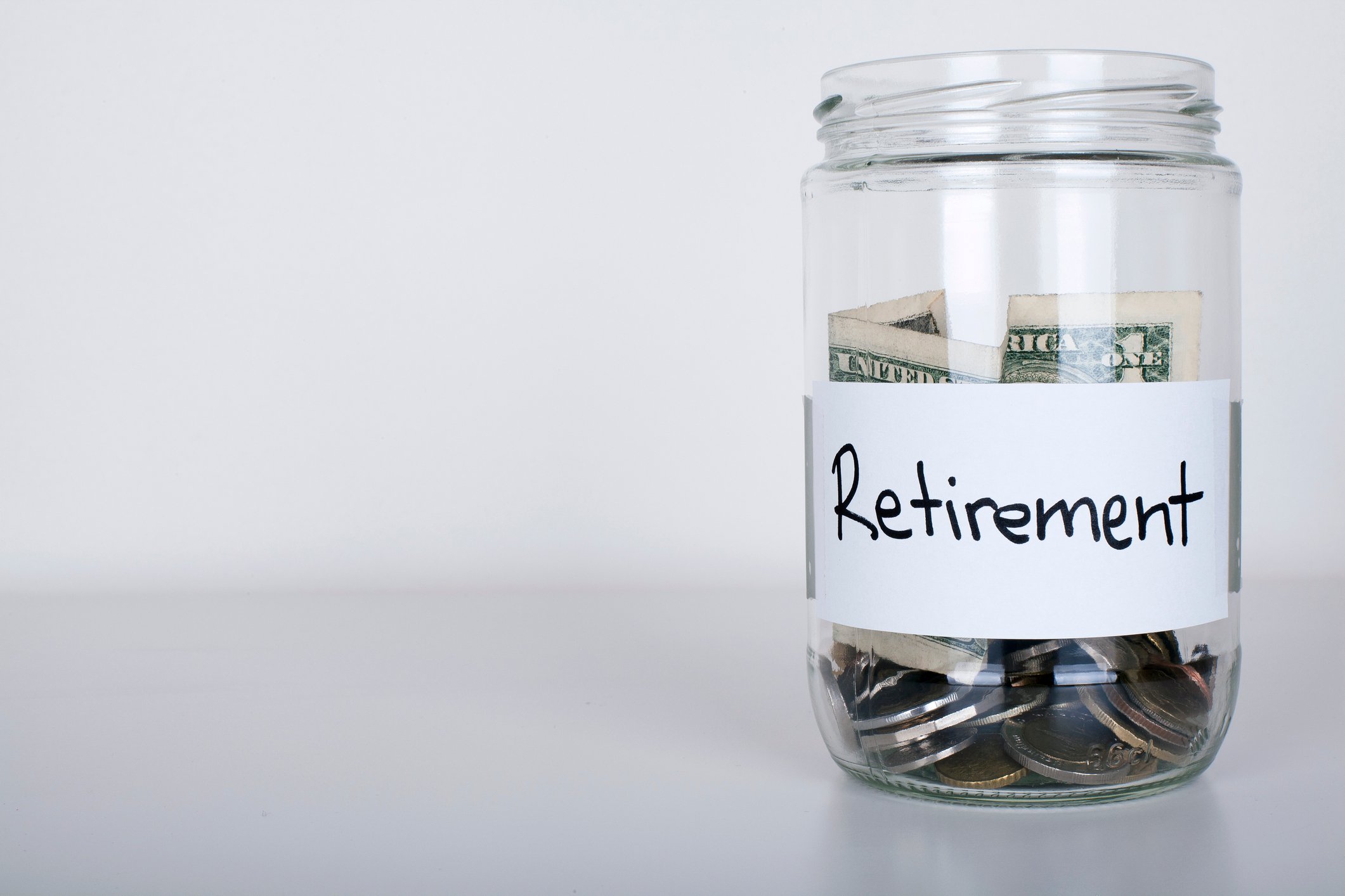 Jar labeled retirement with coins and cash in it.