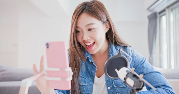A young woman broadcasts a live video from her smartphone.