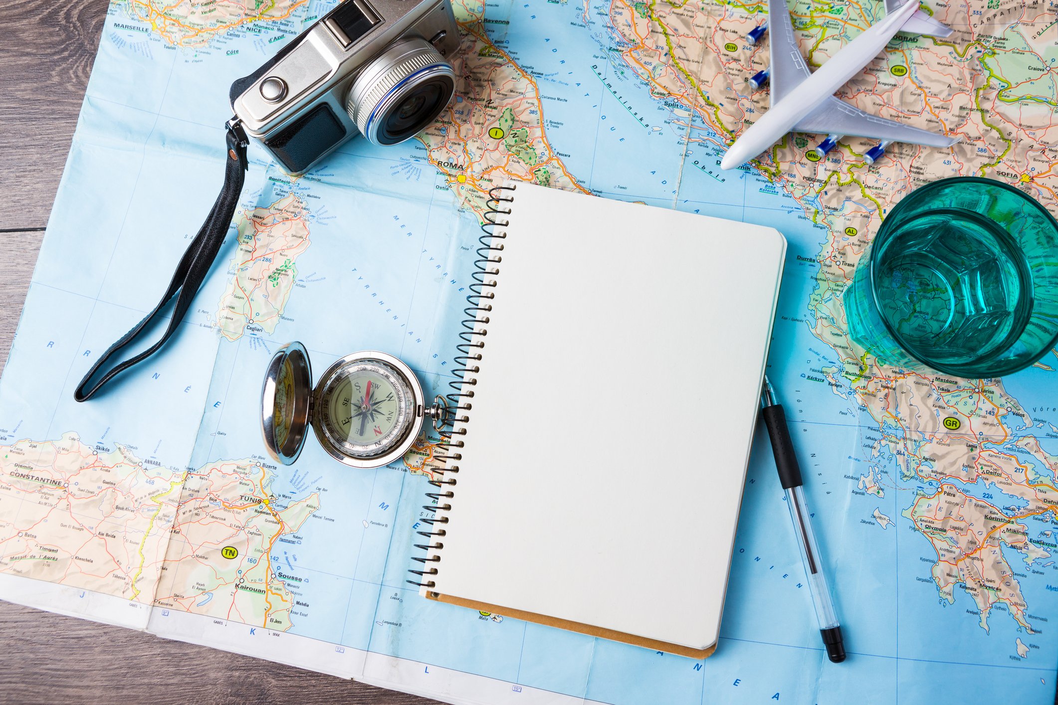 Travel-related items on a desk, including a camera, compass, notebook, and map.
