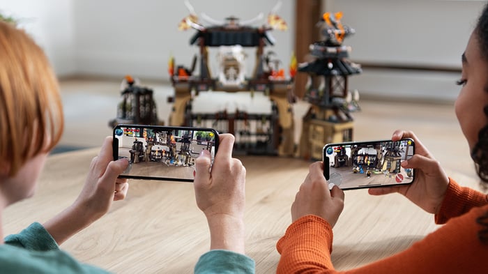 Two children looking at a toy building through their iPhone cameras.