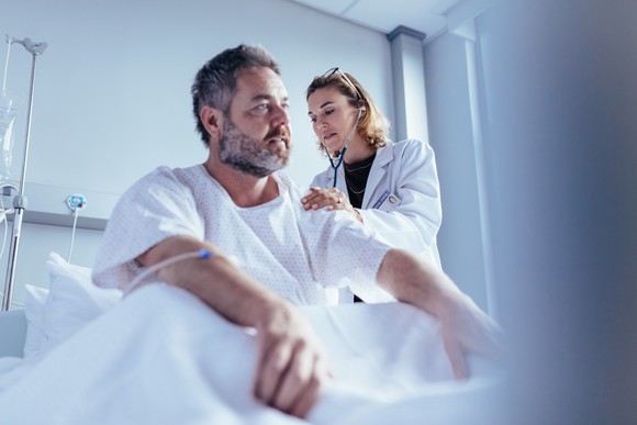 Man in bed being examined by a doctor