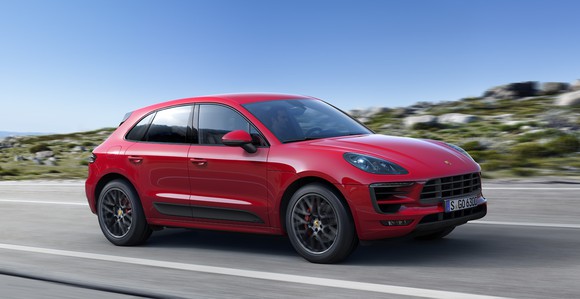 A red Porsche Macan, a sporty compact crossover SUV, on a country road.
