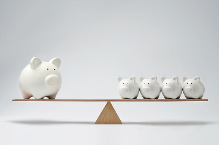 A balanced scale with a giant piggy bank on one end and four smaller piggy banks on the other.