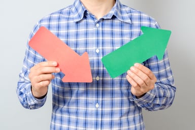 Man holding red down arrow and green up arrow