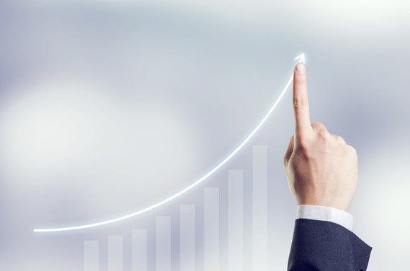 A person pointing to an upwardly sloping chart