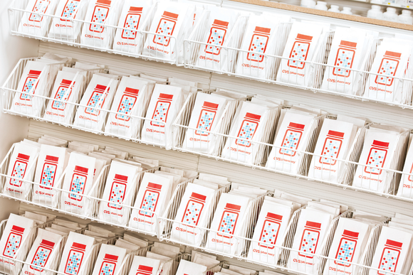 Rows of CVS-labeled prescription bags on a set of shelves.