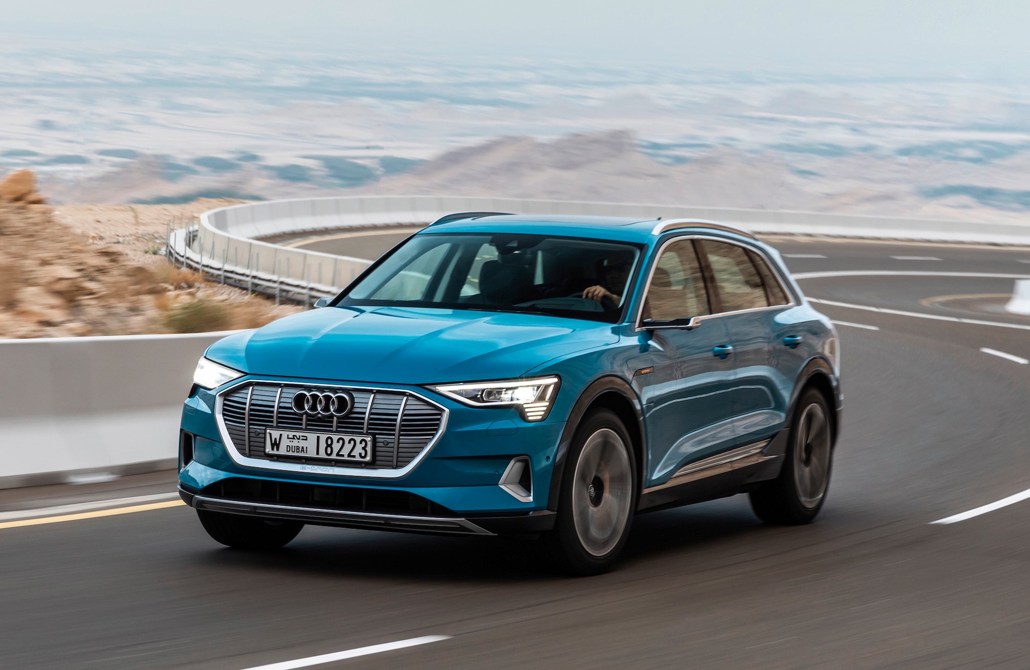 A blue Audi e-tron, a midsize electric crossover SUV, on a winding road. 